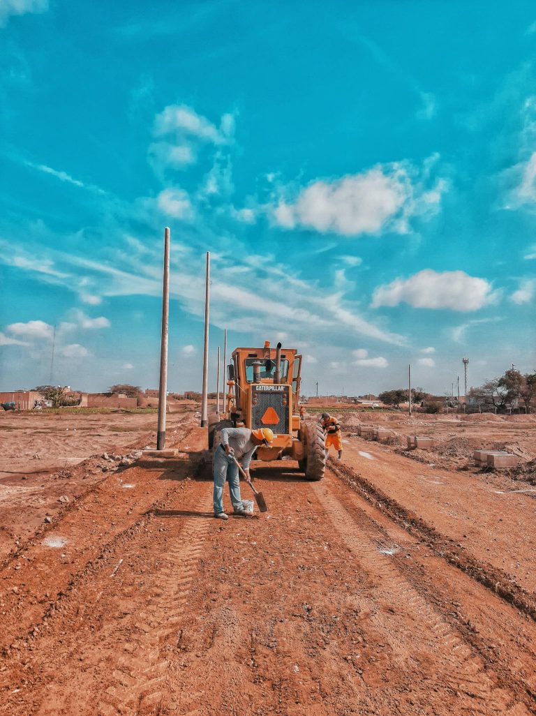 Men working at a construction site with heavy machinery on a sunny day.