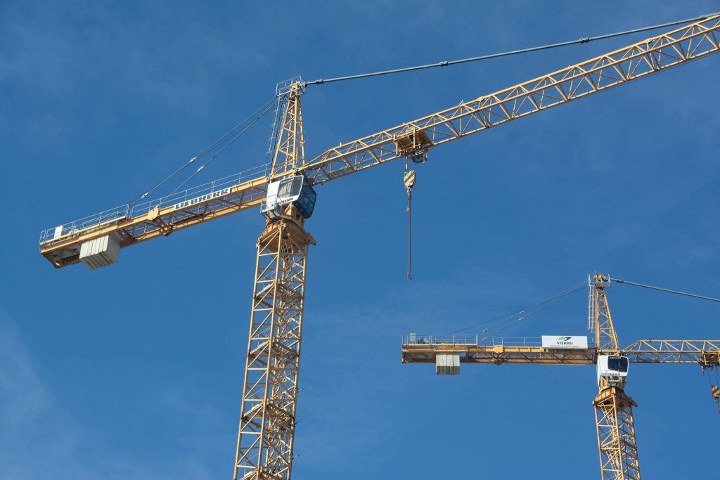 Tower cranes soar high against a bright blue sky, showcasing powerful construction equipment.